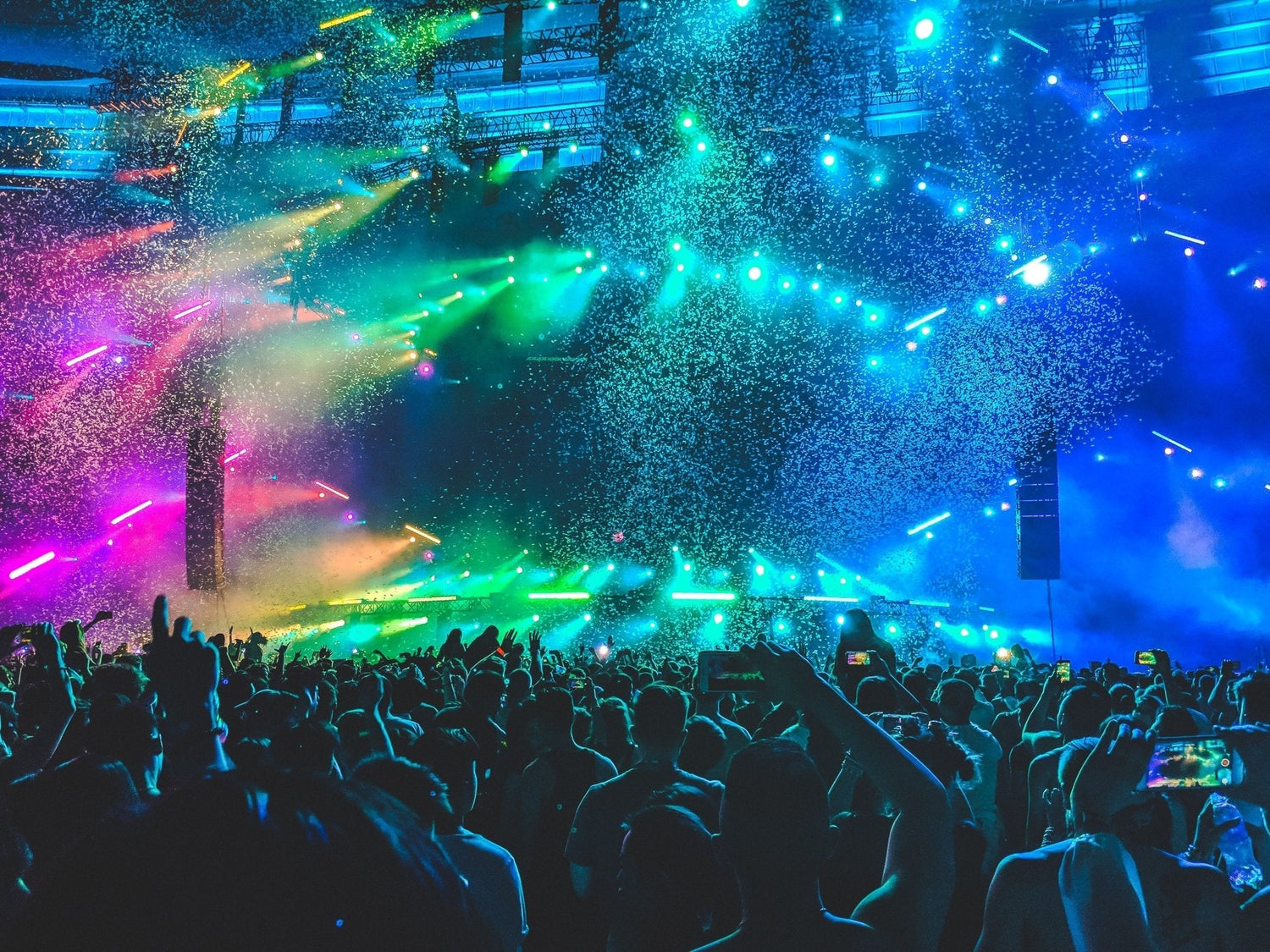 glitter flying through the air at a music festival with lasers and the crowd in rapture